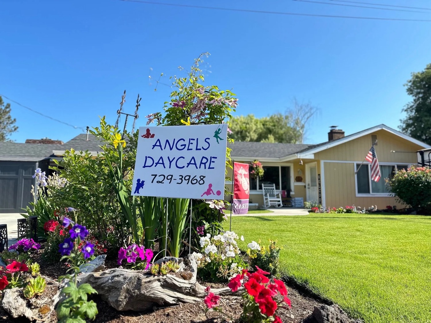 The Angel's Daycare yard sign in a flower bed in front of the house